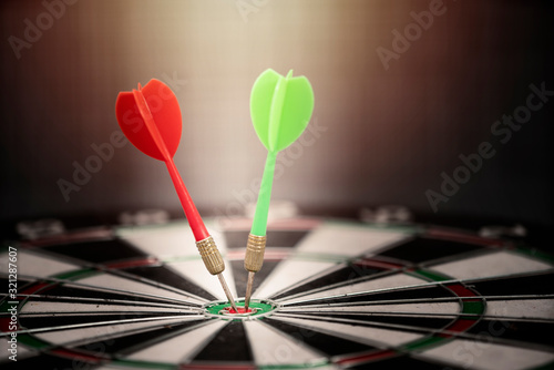 Close up red and green dart arrow hitting on target center of dartboard, business concept 