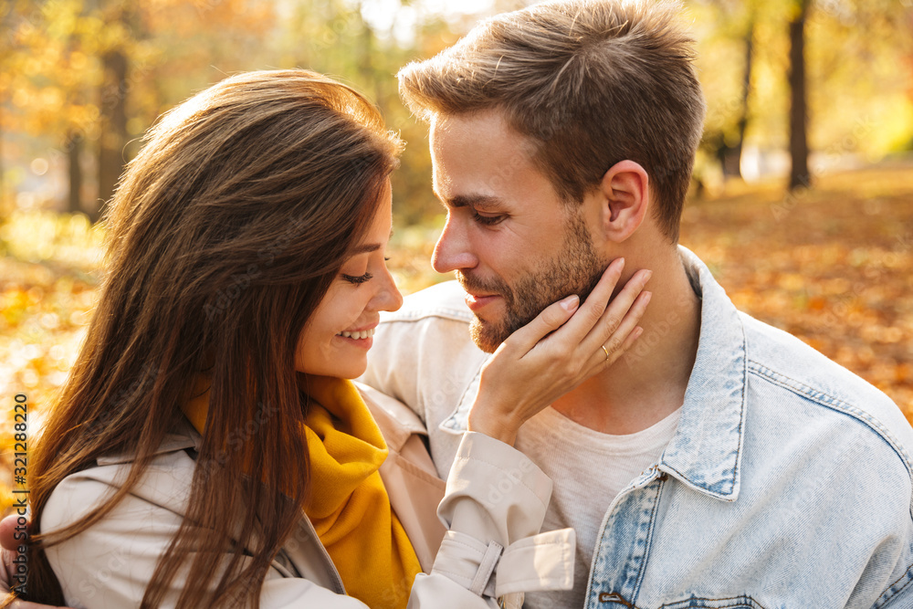 Image of attractive young caucasian couple walking through autumn park