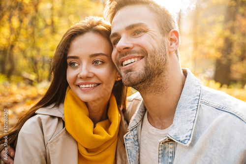Image of attractive young caucasian couple walking through autumn park