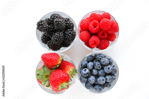 Assortment of fresh berries on a white background. Raspberries  blueberries  blackberries  strawberries in small glasses. Healthy eating. Vegan food. 