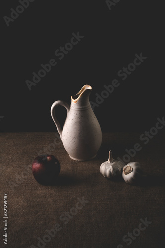 Still life containing garlic, vase and apples