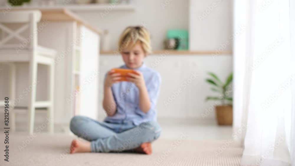 cute blonde boy, cheerful kid playing games on the phone, surfing the internet on gadget cute blonde boy, cheerful kid playing games on the phone, surfing the internet on gadget