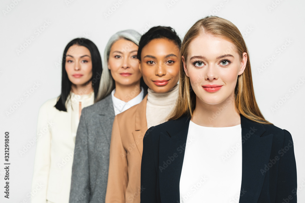 selective focus of four smiling and multicultural businesswomen isolated on white selective focus of four smiling and multicultural businesswomen isolated on white