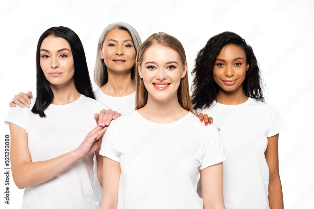 happy multicultural women in white t-shirts looking at camera isolated on white happy multicultural women in white t-shirts looking at camera isolated on white