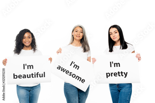 happy multicultural women holding posters with lettering isolated on white