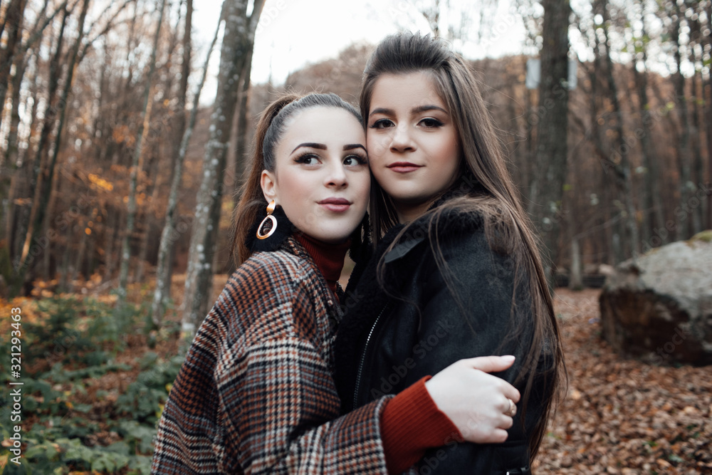 Fototapeta premium Two girls young model walk. Two pretty cuter teenagers shares. Best friends wearing stylish outfit, autumn outdoor.