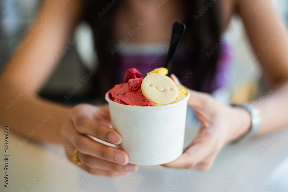Woman hands holding fruity ice cream in hands,Beautiful young woman eating ice cream in cafe. Woman hands holding fruity ice cream in hands,Beautiful young woman eating ice cream in cafe.