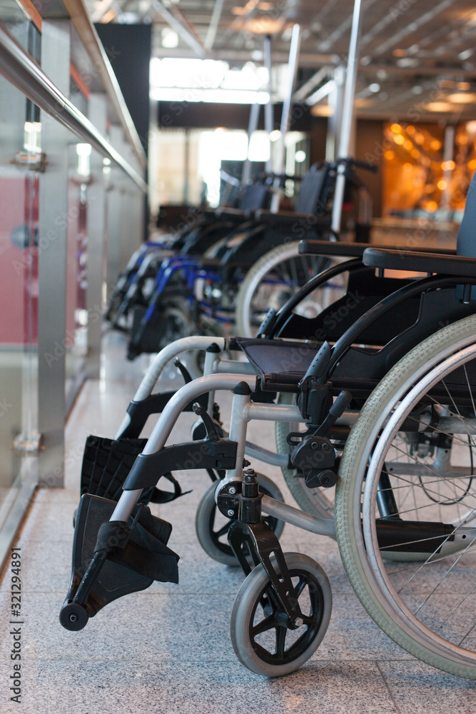 Close-up of wheelchairs in hospital. Invalid chairs in a row. Impairment, disabled people, handicapped accessible environment, medical help Close-up of wheelchairs in hospital. Invalid chairs in a row. Impairment, disabled people, handicapped accessible environment, medical help