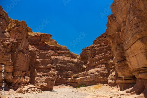 soft focus desert sand stone canyon rocks passage trail between walls foreshortening from below on vivid blue sky background