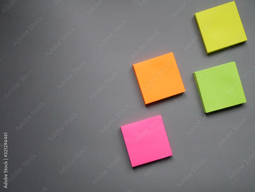 Collection of different colored sheets of note papers ready for your message. Isolated on gray background. Front view. Collection of different colored sheets of note papers ready for your message. Isolated on gray background. Front view.