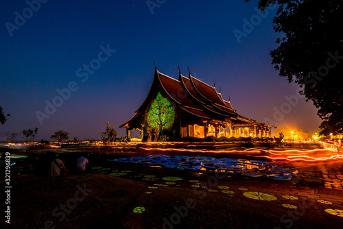 Ubonratchatani, Wat Phu Praw Thailand - February 19, 2019: The day of Buddhism Makha Bucha day or Vesak Day.The people walk with lighted candles in hand around a temple.On a milky way background.