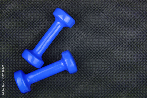 Fitness concept. Weight loss. Blue dumbbells isolated on grey yoga mat. With copy space for text