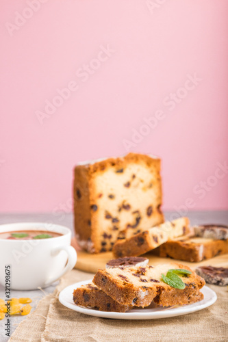 Homemade cake with raisins, dried persimmon and a cup of hot chocolate on a gray and pink background. side view, selective focus.