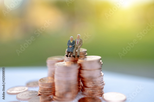 Miniature people: Happy old people sitting on coins stack, Retirement  and Life insurance Concept. photo