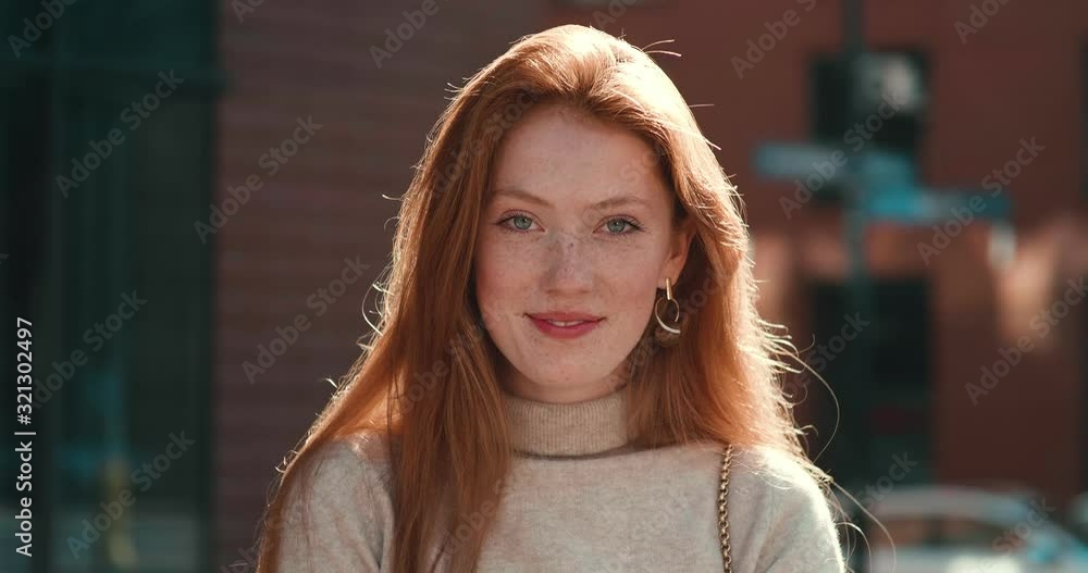 Portrait of Ginger Woman smiling and looking into the camera, posing at sunny day Portrait of Ginger Woman smiling and looking into the camera, posing at sunny day
