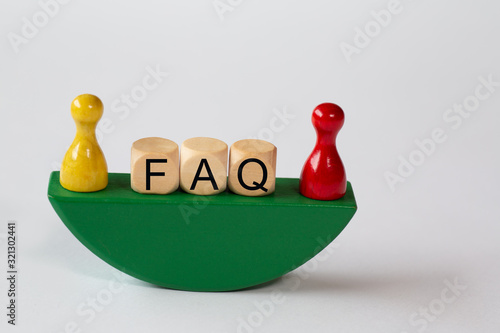 FAQ - the abbreviation for Frequently Asked Questions are wooden letters on a stylized boat. On the right and left a wooden figure in yellow and red photo