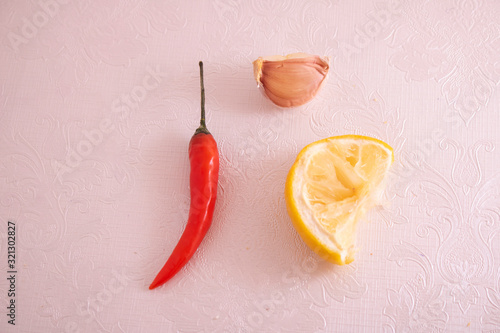 vegetarian concept, chilli pepper, garlic and lemon on pink paper , top view food
