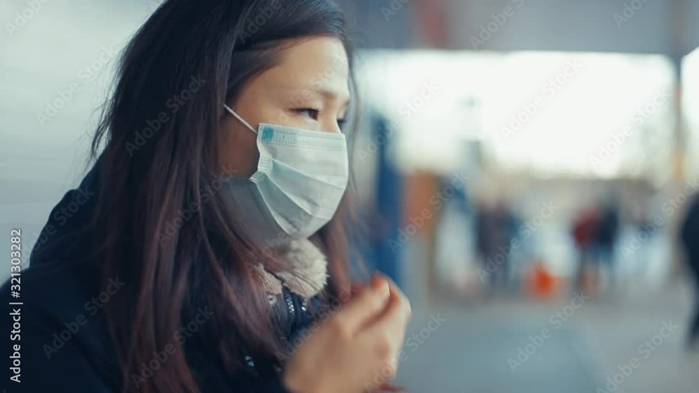 Sick girl with Chinese coronavirus in a public place. Wearing a protective mask prevents infection of other people. The woman has chills and fever, symptoms of infection. Sick girl with Chinese coronavirus in a public place. Wearing a protective mask prevents infection of other people. The woman has chills and fever, symptoms of infection.