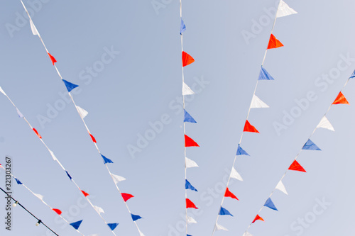 multicolored flags flutter in the wind over a street fair