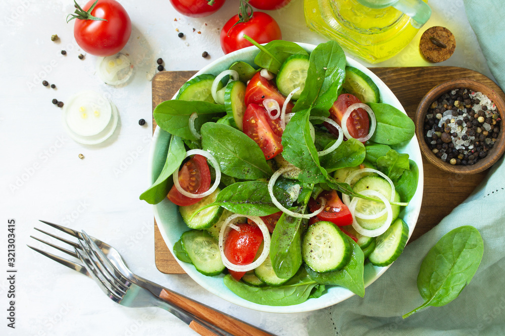Diet menu. Healthy vegetable salad of fresh tomato, cucumber, onion and spinach on slate, stone or concrete background. Top view flat lay background. Diet menu. Healthy vegetable salad of fresh tomato, cucumber, onion and spinach on slate, stone or concrete background. Top view flat lay background.