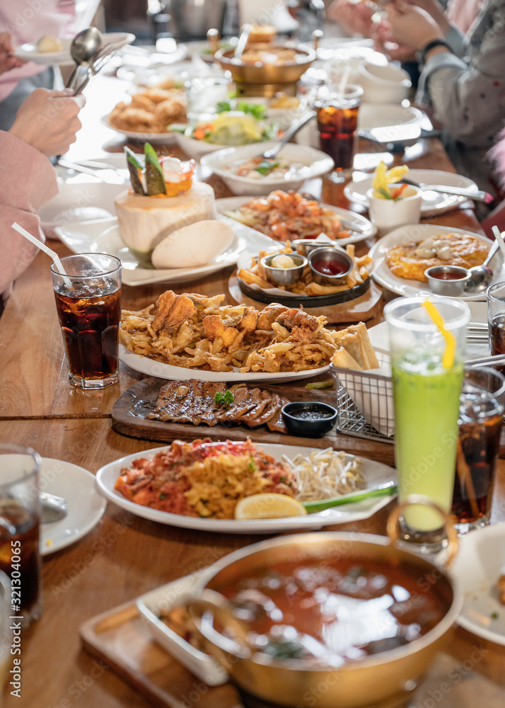Various kind of gourmet food and drink with family eating on wooden table