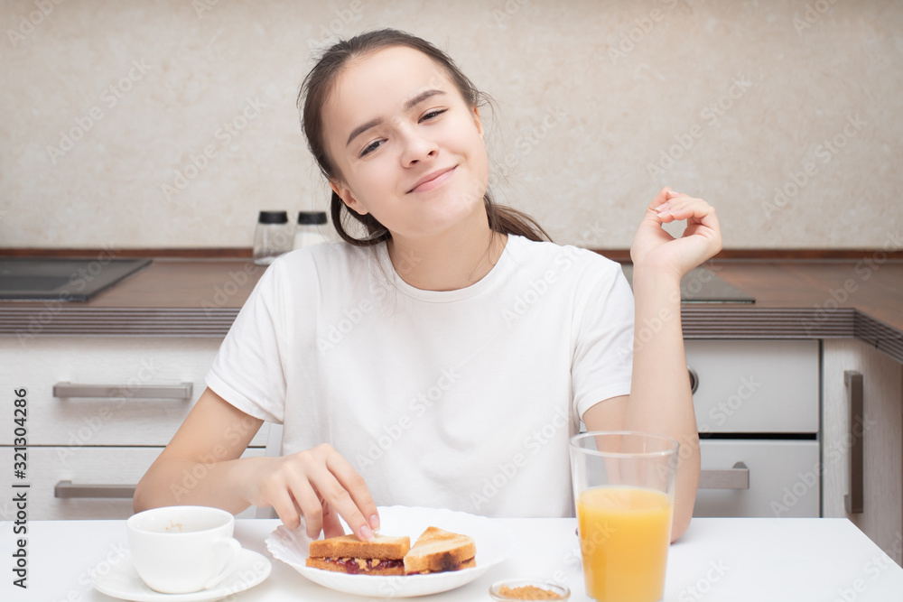 Girl eating a sandwich in the morning for breakfast and drinking aromatic coffee