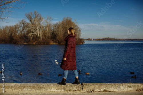 girl in a red jacket on a background of blue water with ducks