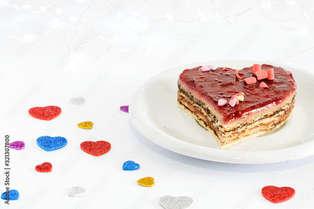 Valentines day. Romantic sweet heart cake on the white plate and white background with little colorful hearts. Valentines day. Romantic sweet heart cake on the white plate and white background with little colorful hearts.