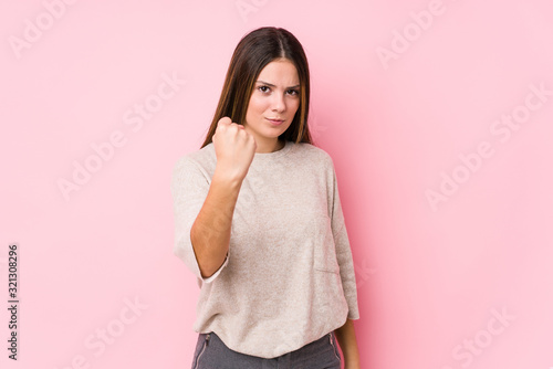 Young caucasian woman posing isolated showing fist to camera  aggressive facial expression.