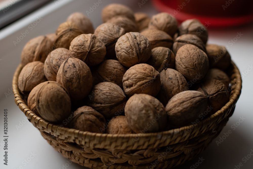 Small wicker basket filled with walnuts on a white background Small wicker basket filled with walnuts on a white background