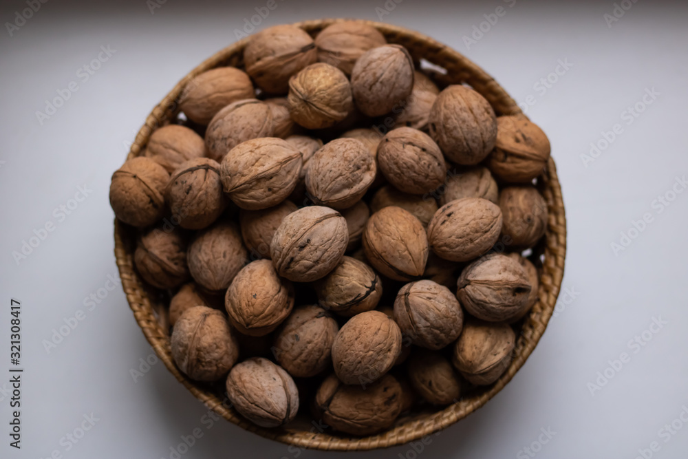 Small wicker basket filled with walnuts on a white background Small wicker basket filled with walnuts on a white background