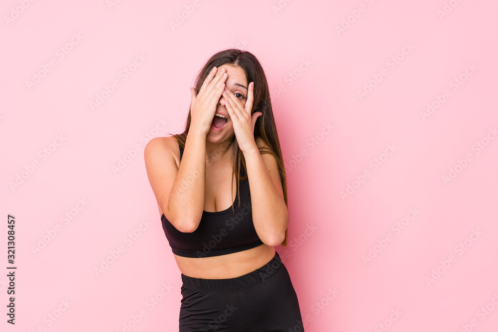 Young fitness caucasian woman isolated blink through fingers frightened and nervous. Young fitness caucasian woman isolated blink through fingers frightened and nervous.