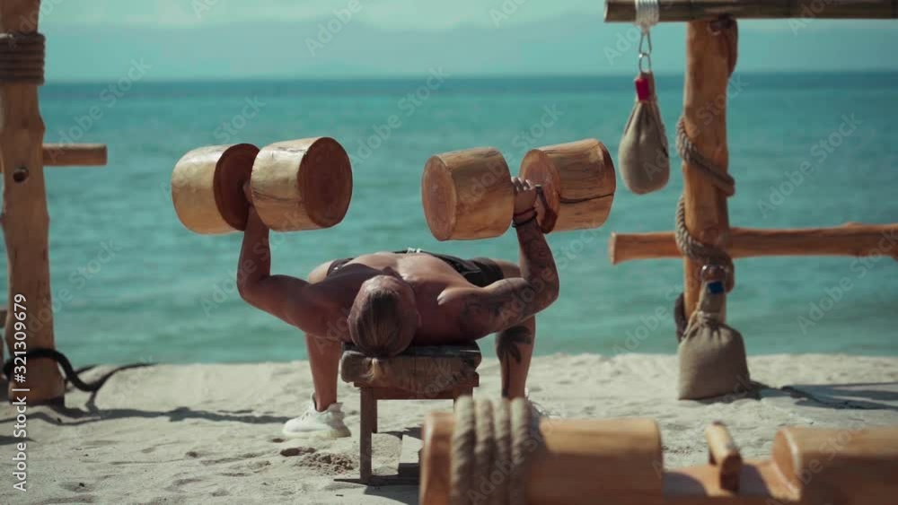 Fitness man training on the beach. Athlete doing cross fitness workout outdoor. Sport fit exercise. Eco gym