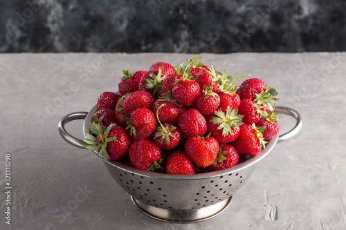 Fresh juicy strawberries from the garden in an iron bowl on the table. Heap of fresh strawberries in an iron bowl on rustic white wooden background. Fresh organic berries macro. Free space for text.