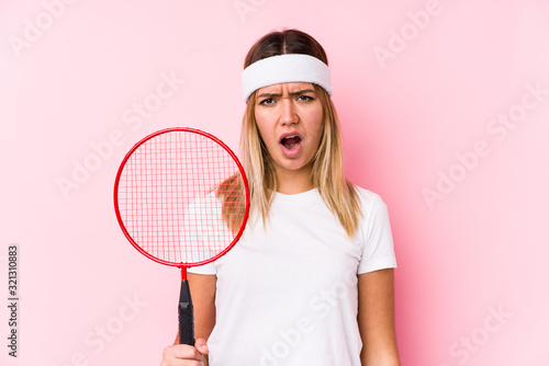 Young woman playing badminton isolated screaming very angry and aggressive.