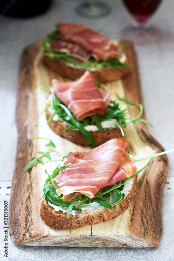 Traditional italian appetizer bruschetta of toasted bread with cottage cheese, arugula and prosciutto. Traditional italian appetizer bruschetta of toasted bread with cottage cheese, arugula and prosciutto.