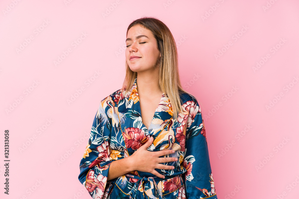 Young caucasian woman wearing pajamas touches tummy, smiles gently, eating and satisfaction concept. Young caucasian woman wearing pajamas touches tummy, smiles gently, eating and satisfaction concept.
