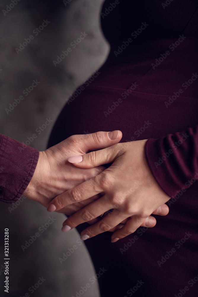 Cropped image of beautiful pregnant woman and her handsome husband hugging the tummy