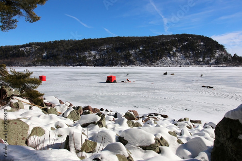 Ice age nature. Winter landscape in the DevilÕs Lake State Perk from west bluff hiking trail, covered by snow. Bright red tents and fishermen on the frozen lake. Midwest USA, Wisconsin, Baraboo area.