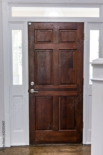 Solid wood dark stained front door in a home with vaulted ceilings and transom windows © Ursula Page
