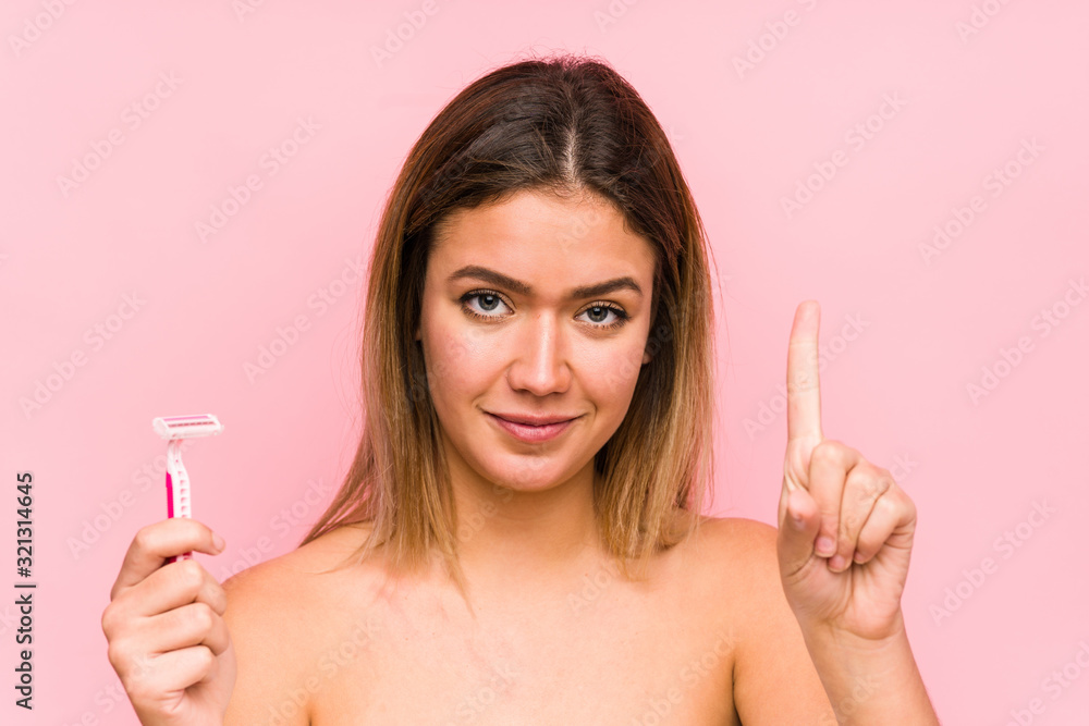 Young caucasian woman holding a razor blade isolated Young caucasian woman holding a hairbrush isolated showing number one with finger.< mixto > Young caucasian woman holding a razor blade isolated Young caucasian woman holding a hairbrush isolated showing number one with finger.< mixto >