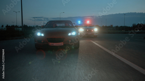 Amazing night scene. Police on duty. Side view of professional traffic cops detaining and arresting drunk driver. Close-up policeman leading scared young man to the car hood to handcuff him. © Fractal Pictures