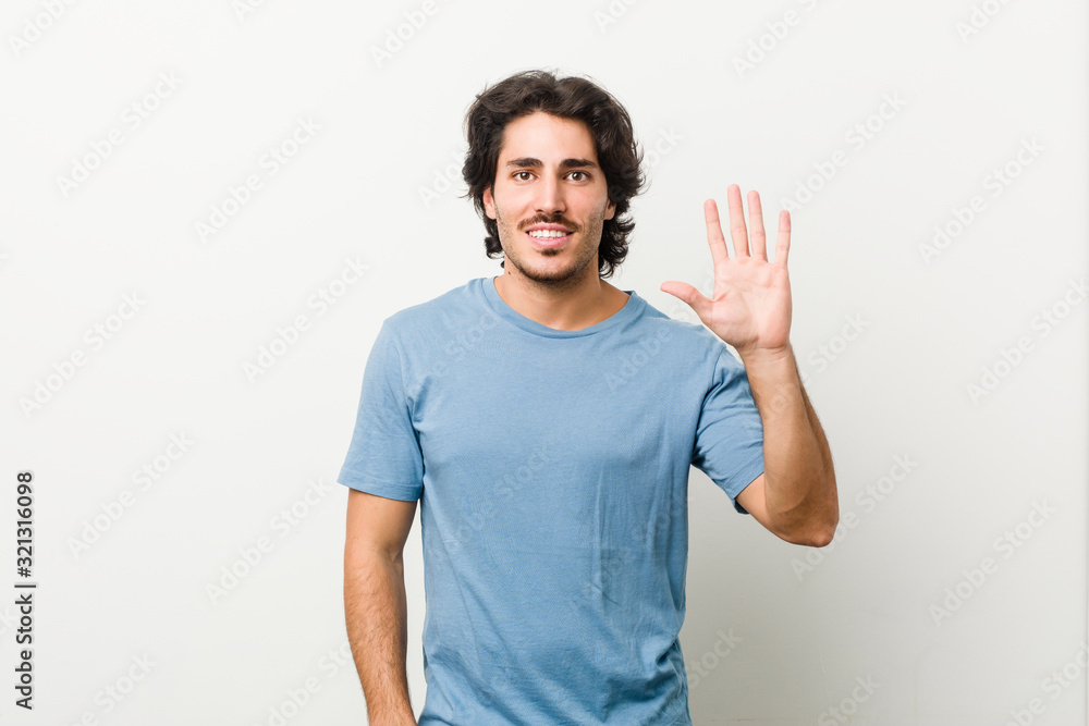 Young handsome man against a white background smiling cheerful showing number five with fingers. Young handsome man against a white background smiling cheerful showing number five with fingers.