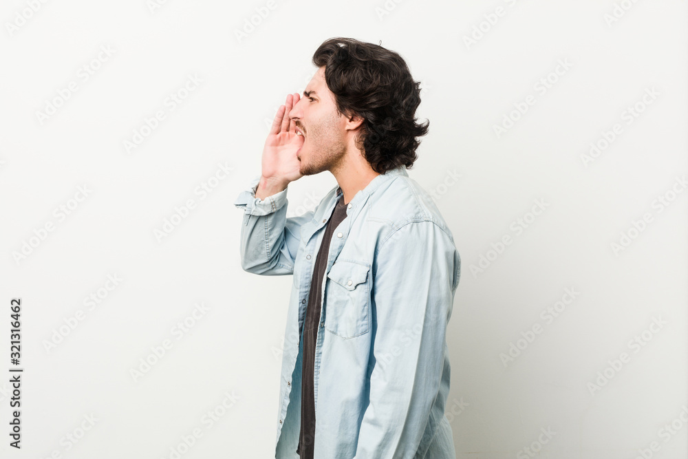 Young handsome man against a white background shouting and holding palm near opened mouth. Young handsome man against a white background shouting and holding palm near opened mouth.