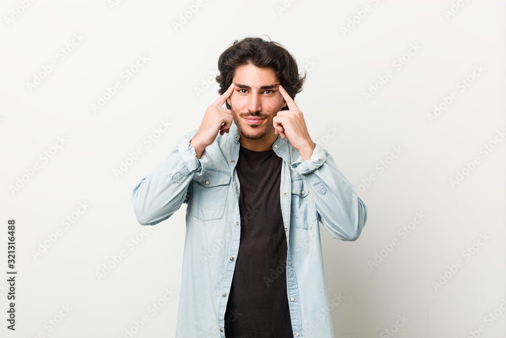 Young handsome man against a white background focused on a task, keeping forefingers pointing head. Young handsome man against a white background focused on a task, keeping forefingers pointing head.