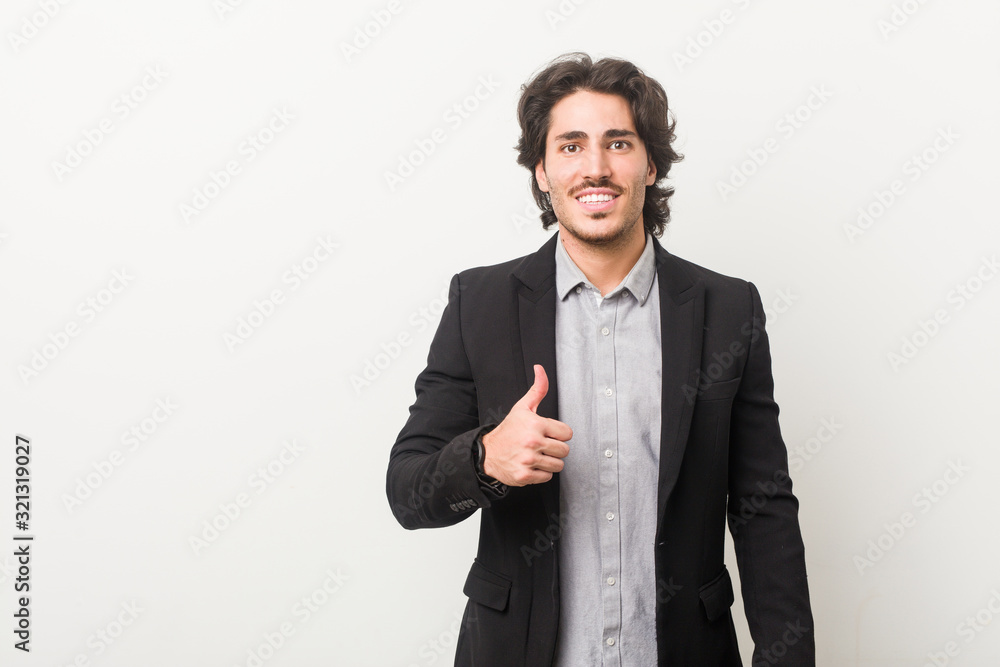 Young business man against a white background smiling and raising thumb up Young business man against a white background smiling and raising thumb up