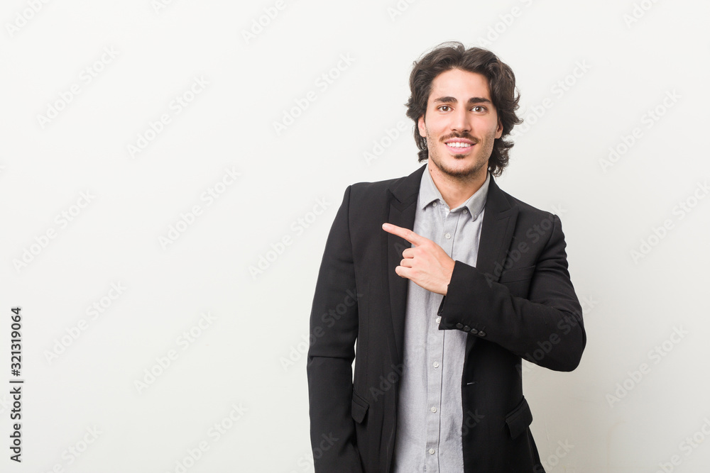Young business man against a white background smiling and pointing aside, showing something at blank space. Young business man against a white background smiling and pointing aside, showing something at blank space.