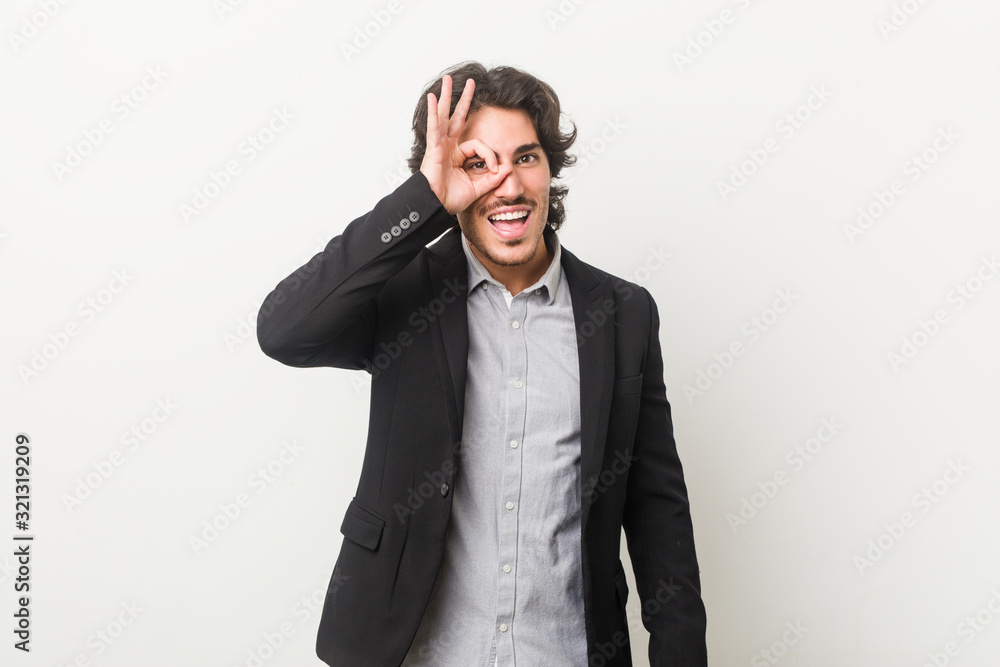 Young business man against a white background excited keeping ok gesture on eye. Young business man against a white background excited keeping ok gesture on eye.