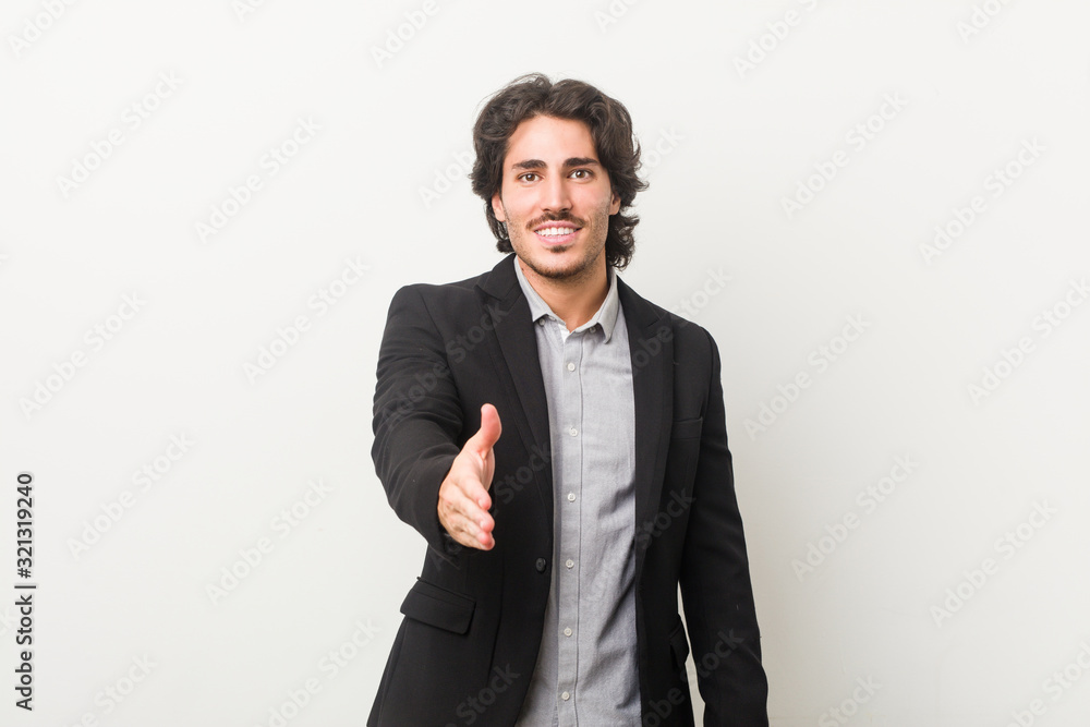 Young business man against a white background stretching hand at camera in greeting gesture. Young business man against a white background stretching hand at camera in greeting gesture.