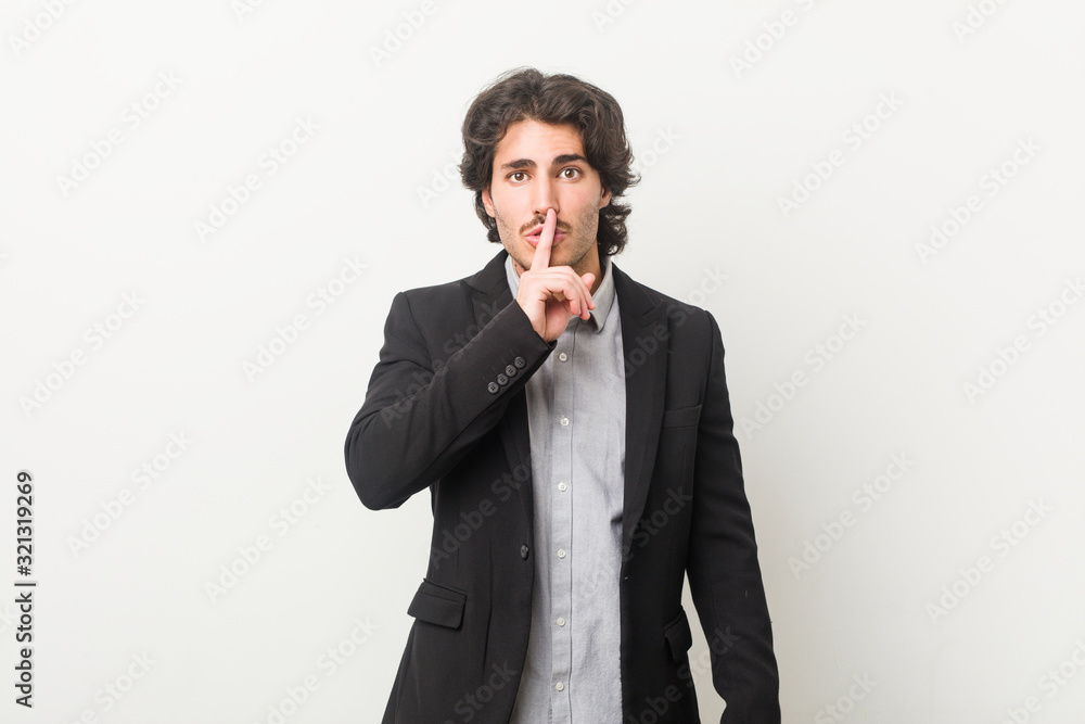 Young business man against a white background keeping a secret or asking for silence. Young business man against a white background keeping a secret or asking for silence.